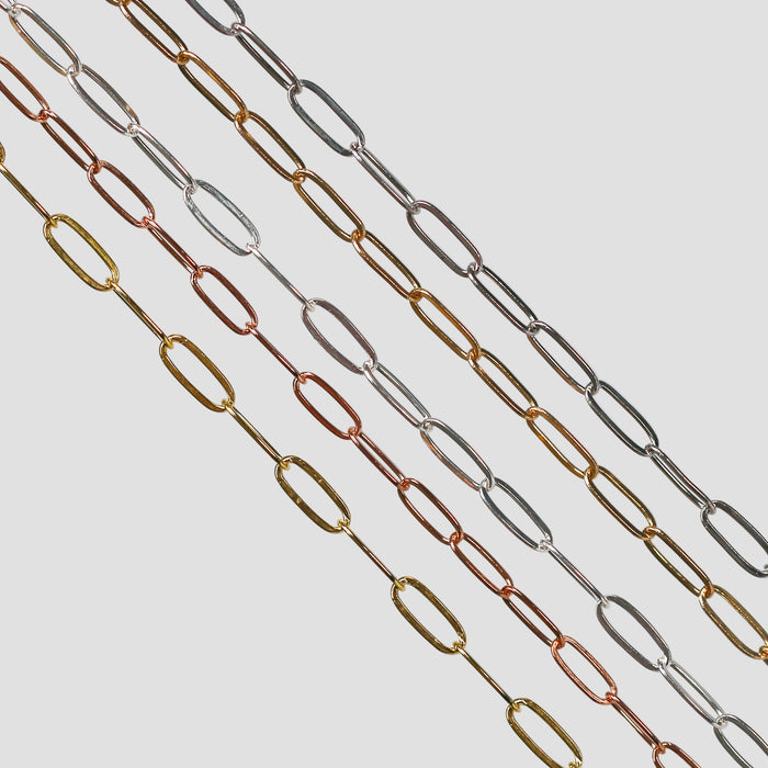 Flat elongated oval chains laid out side by side in different metal types. 14 karat gold, 14/20 gold filled, and sterling silver options are depicted.