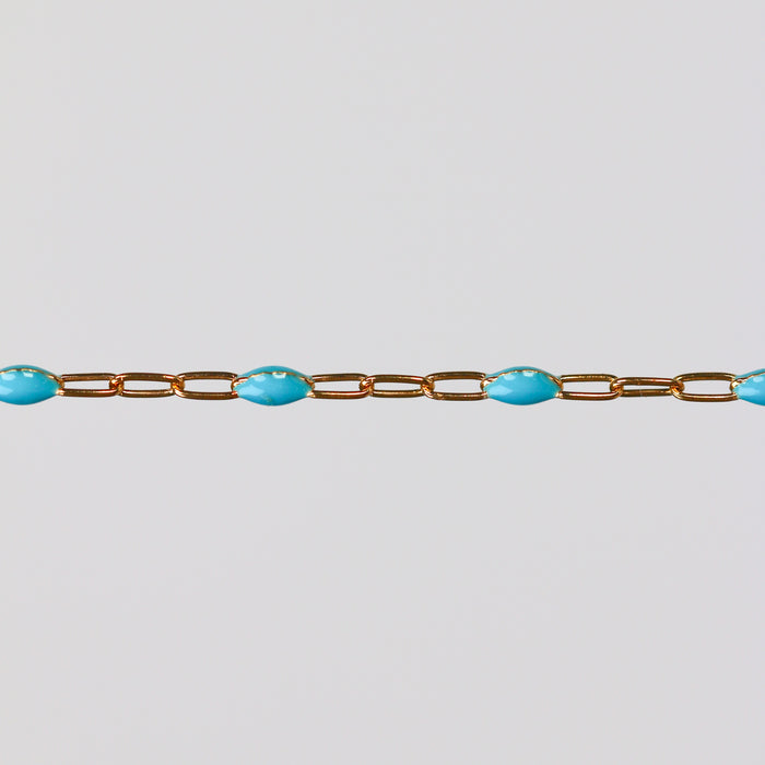 Gold chain with blue turquoise enamel on a light gray background
