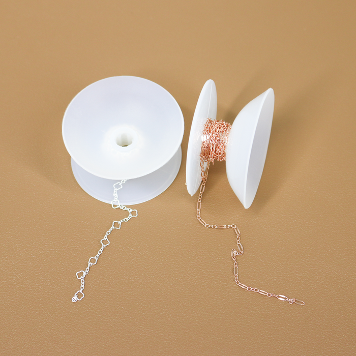Delicate chain for permanent jewelry wrapped around little storage spools.
