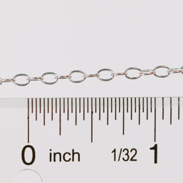 Silver chain next to a ruler on a white background