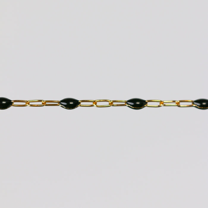 Gold chain with black enamel on a light gray background