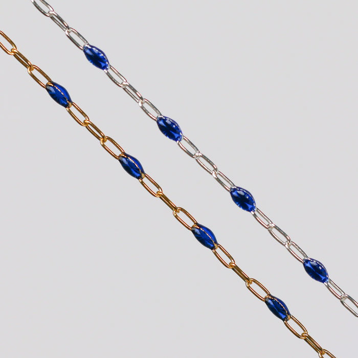 Two blue enamel permanent jewelry chains. One chain is yellow gold and the other is silver.