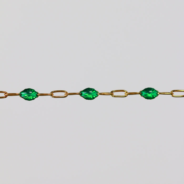 Yellow gold permanent jewelry chain with cable links and green enamel on a light gray background