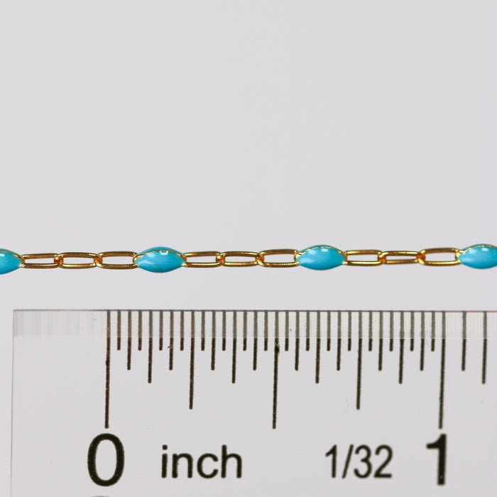 Gold chain with blue enamel beads next to a ruler for scale on a white background