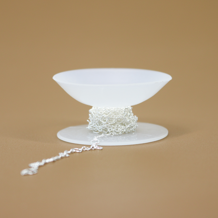 Pictured is an accessory for permanent jewelry chain on an organizer and storage bobbin spool.