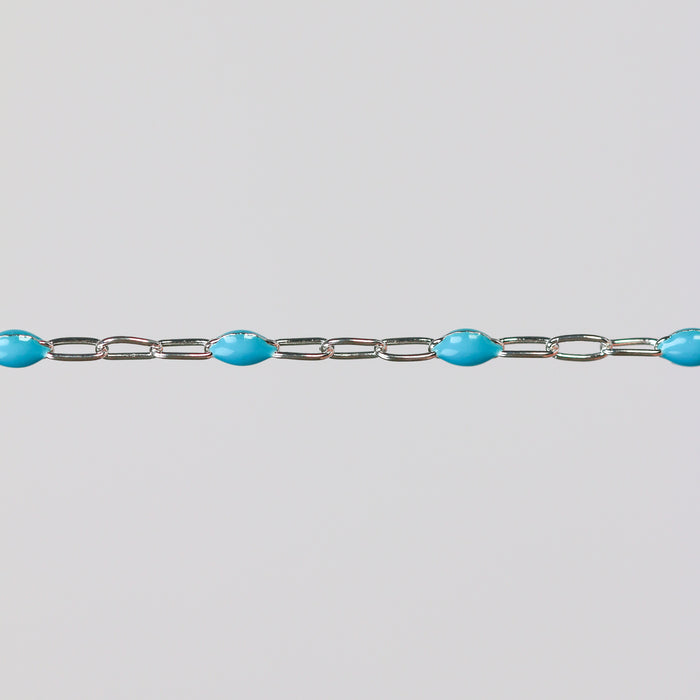 Silver bracelet chain with turquoise enamel on it over a gray background