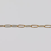 Yellow gold paperclip chain on a light gray background.