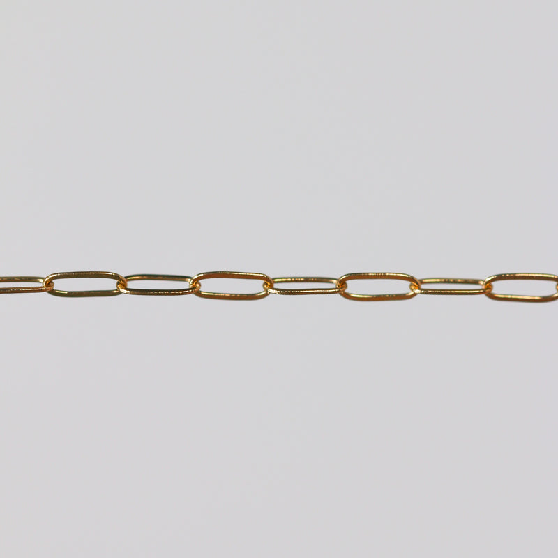 Yellow gold paperclip chain on a light gray background.