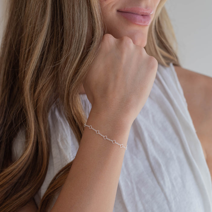 Woman wearing a delicate sterling silver chain bracelet on a plain background