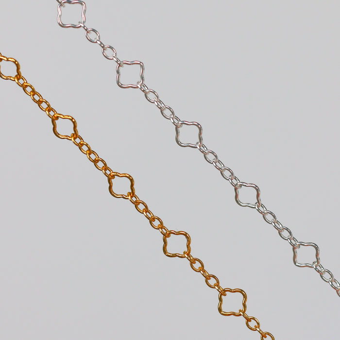 Gold and Silver Chain Closeup with Clover Links on a Gray Background