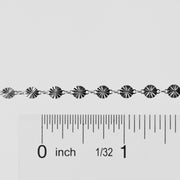 Silver bracelet with a ruler for scale on a white background