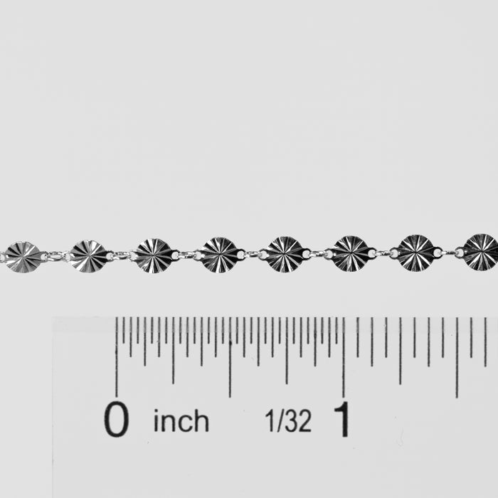 Silver bracelet with a ruler for scale on a white background