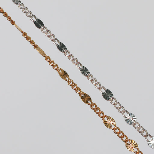 Two figaro chains with starburst links on a gray background.