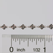 Permanent jewelry chain shown being measured against a ruler for size.