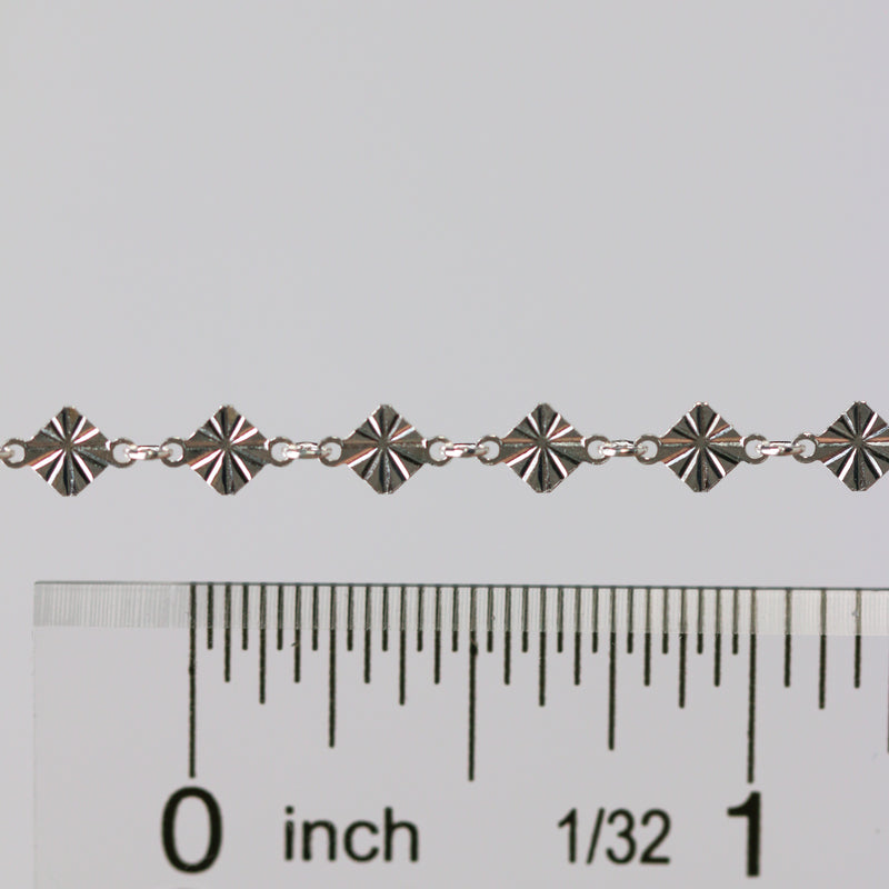 Permanent jewelry chain shown being measured against a ruler for size.