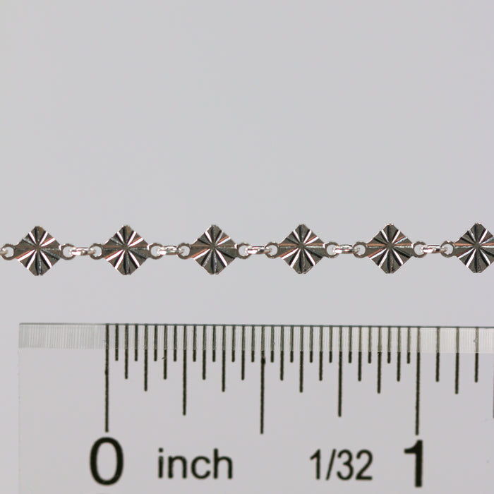 Permanent jewelry chain shown being measured against a ruler for size.