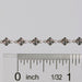Permanent jewelry chain shown being measured against a ruler for size.