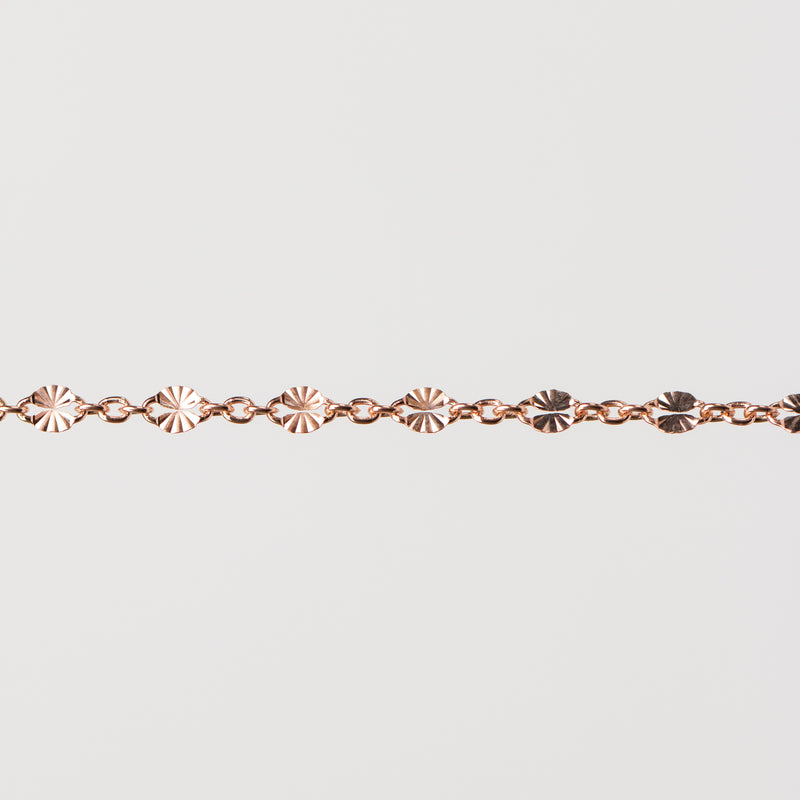 Zoomed in photo of the Brielle chain with shiny starburst links that catch the light on a plain background.
