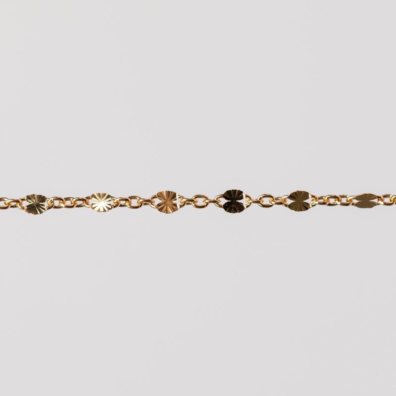 Zoomed in photo of a starburst shiny permanent jewelry chain in yellow gold filled.