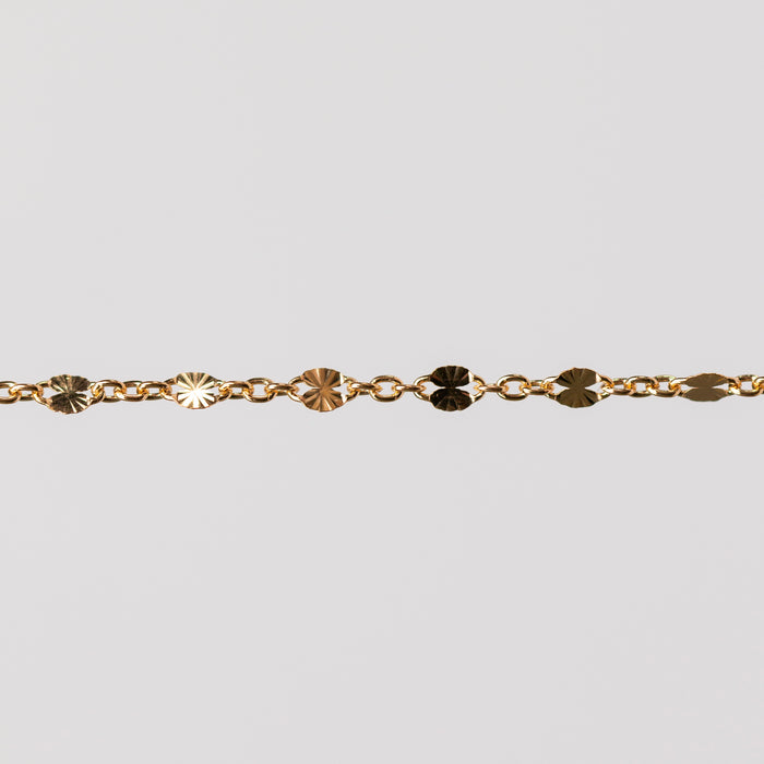 Zoomed in photo of a starburst shiny permanent jewelry chain in yellow gold filled.