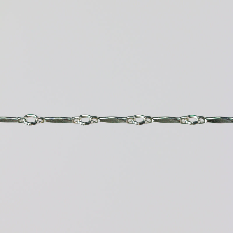 Silver dapped brittany chain close up on a light gray background.