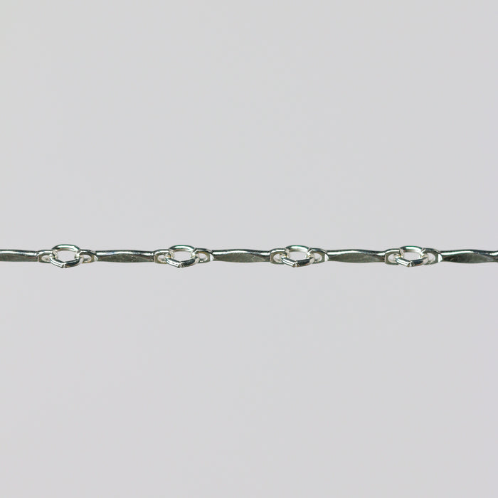 Silver dapped brittany chain close up on a light gray background.