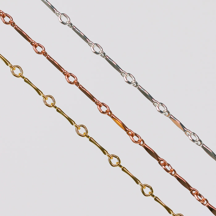Three dapped bar and link chains for permanent jewelry on a light gray background