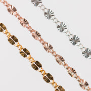 Three Figaro Permanent Jewelry chains of different metal types on a light gray background