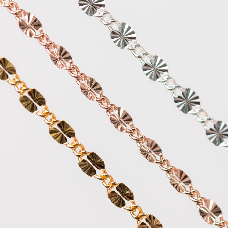 Three Figaro Permanent Jewelry chains of different metal types on a light gray background