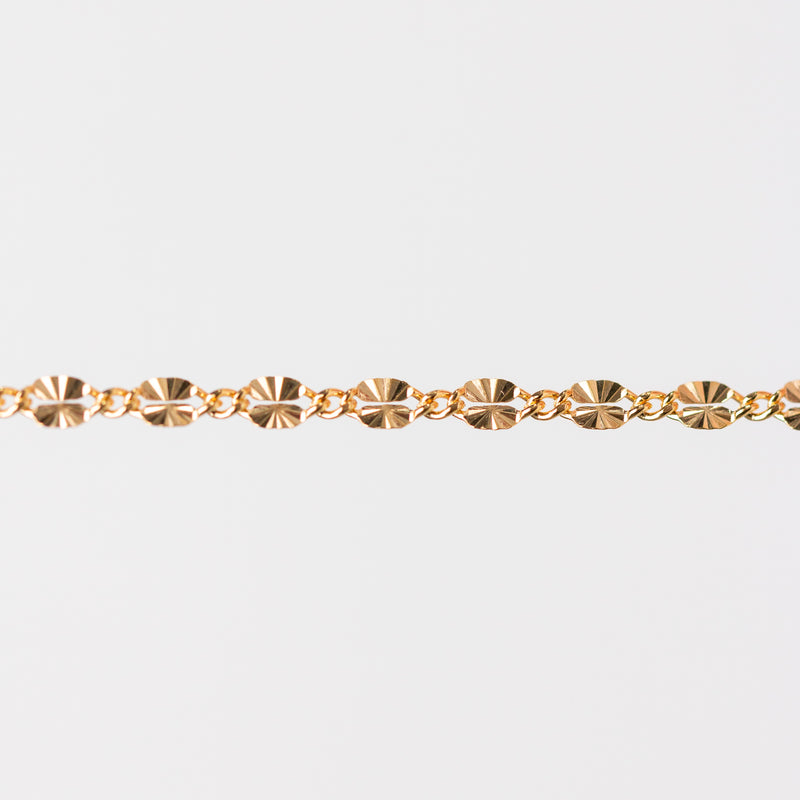 Gold chain bracelet closeup on a light gray background