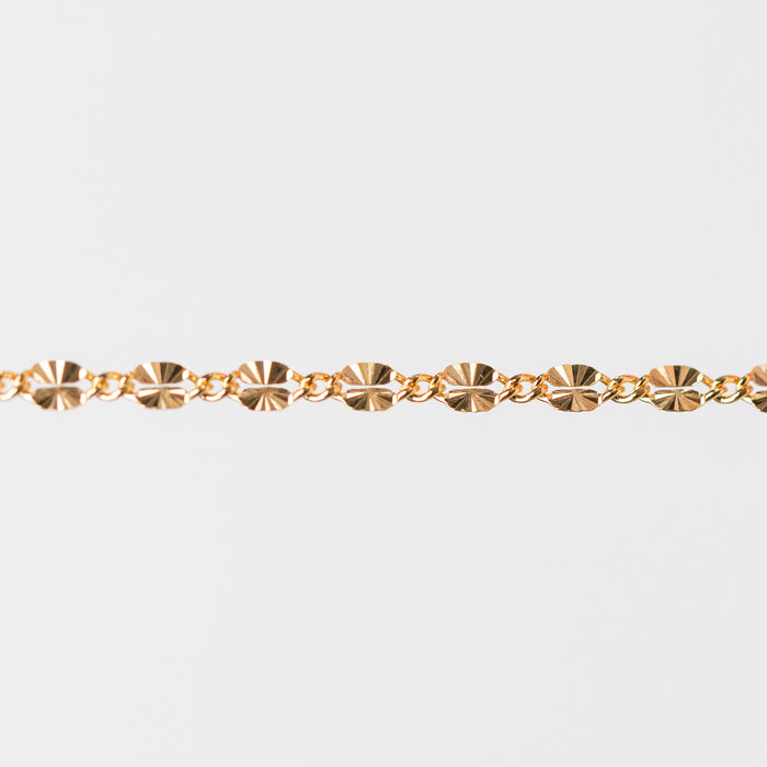 Gold chain bracelet closeup on a light gray background