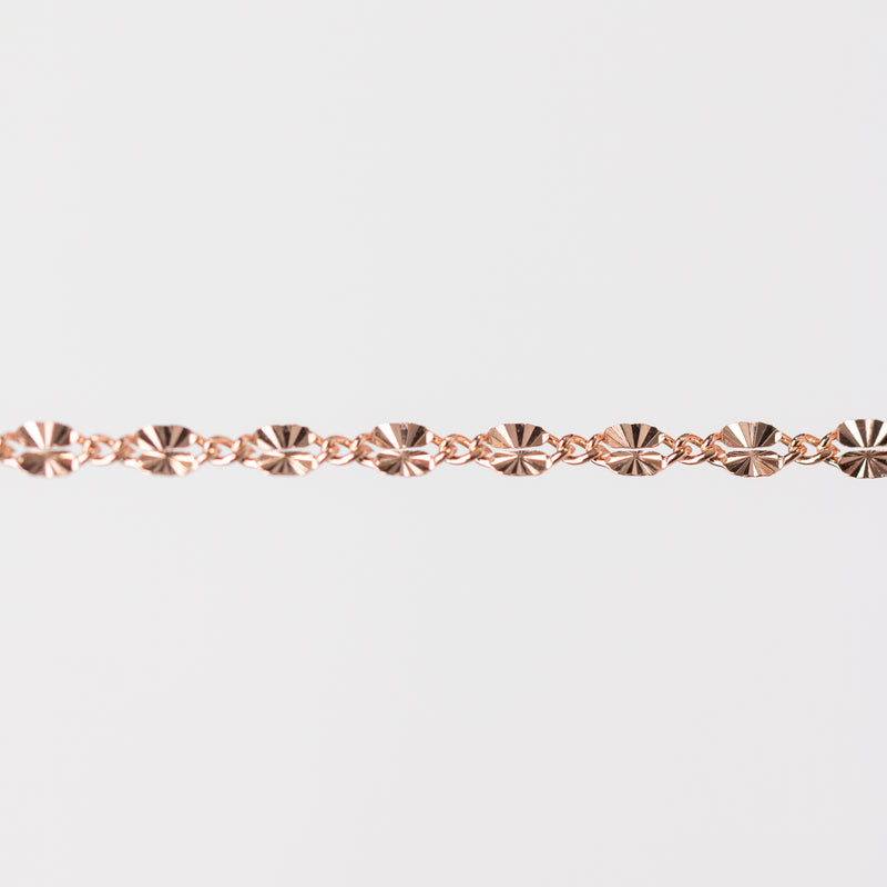Rose gold chain bracelet closeup on a light gray background