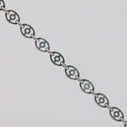 Silver chain with disks linked together. The disks have holes in them that give the chain a light, airy look.