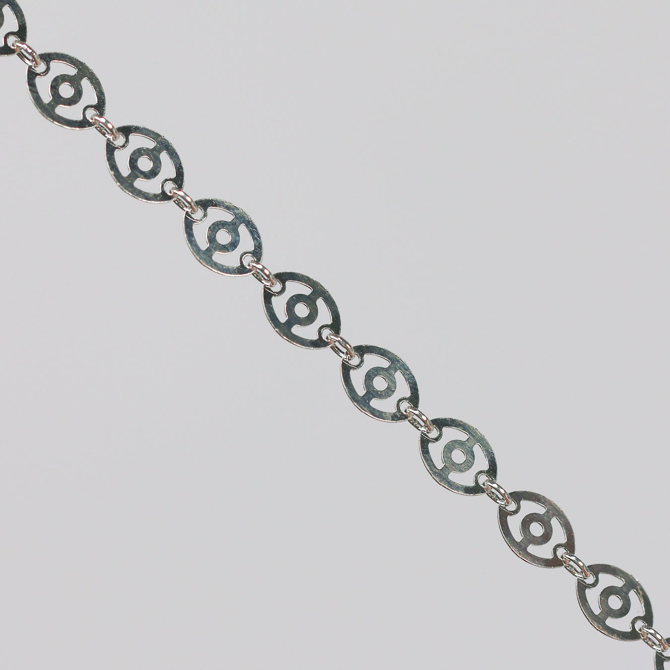 Silver chain with disks linked together. The disks have holes in them that give the chain a light, airy look.