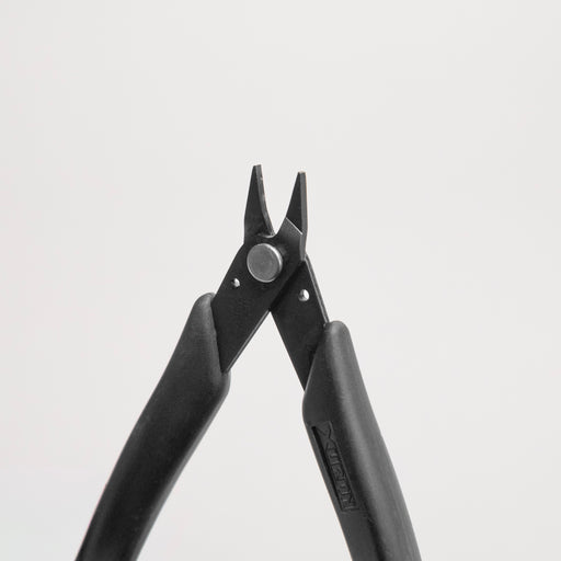 Pair of black finely tipped pliers on a light gray background