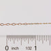 Gold chain with a ruler for scale on a white background