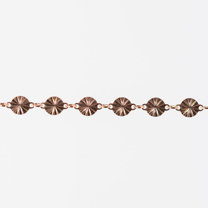 Rose gold bracelet with circular links on a white background