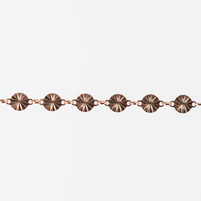 Rose gold bracelet with circular links on a white background
