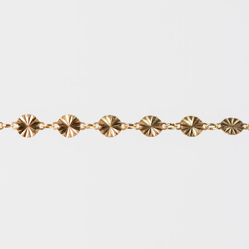 Gold bracelet with circular hammered links on a white background