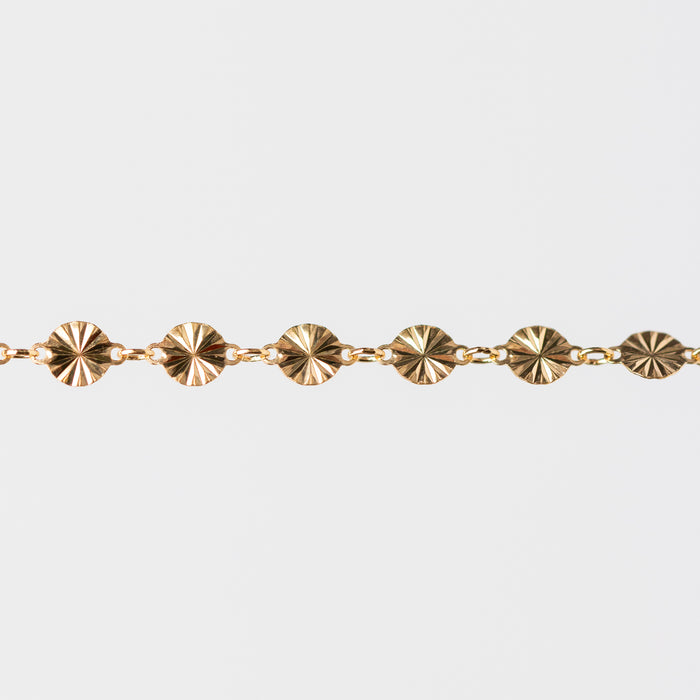Gold bracelet with circular hammered links on a white background