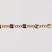 Gold chain bracelet on gray background showing the starburst design up close.