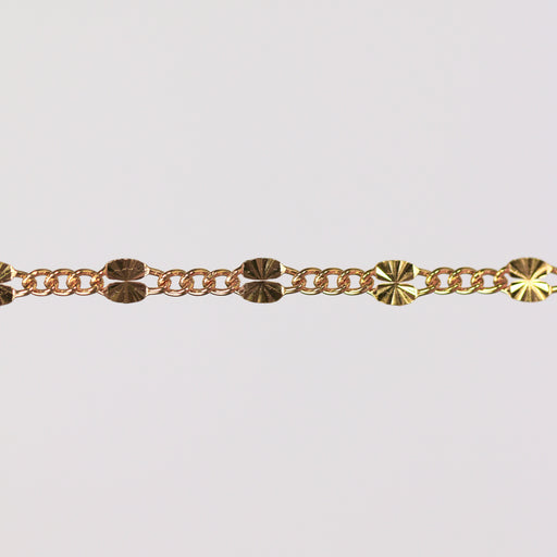 Gold chain bracelet on gray background showing the starburst design up close.