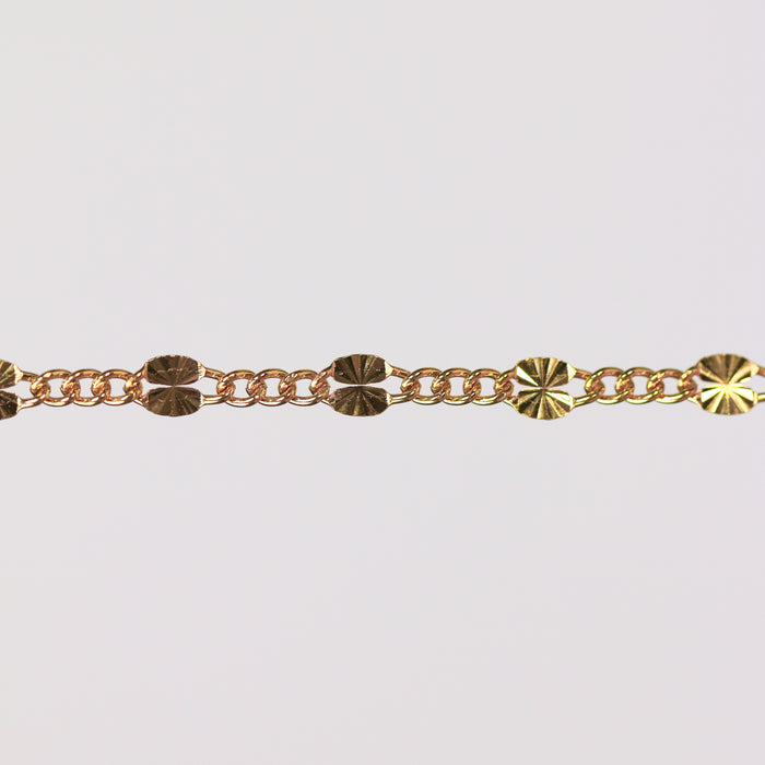 Gold chain bracelet on gray background showing the starburst design up close.