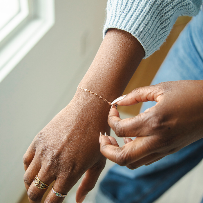 Person adjusting a bracelet on their wrist with a soft focus background