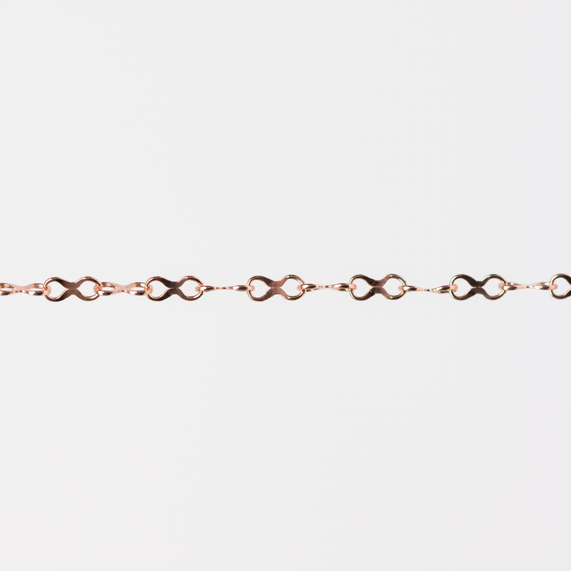 Rose gold infinity chain bracelet on a light gray background