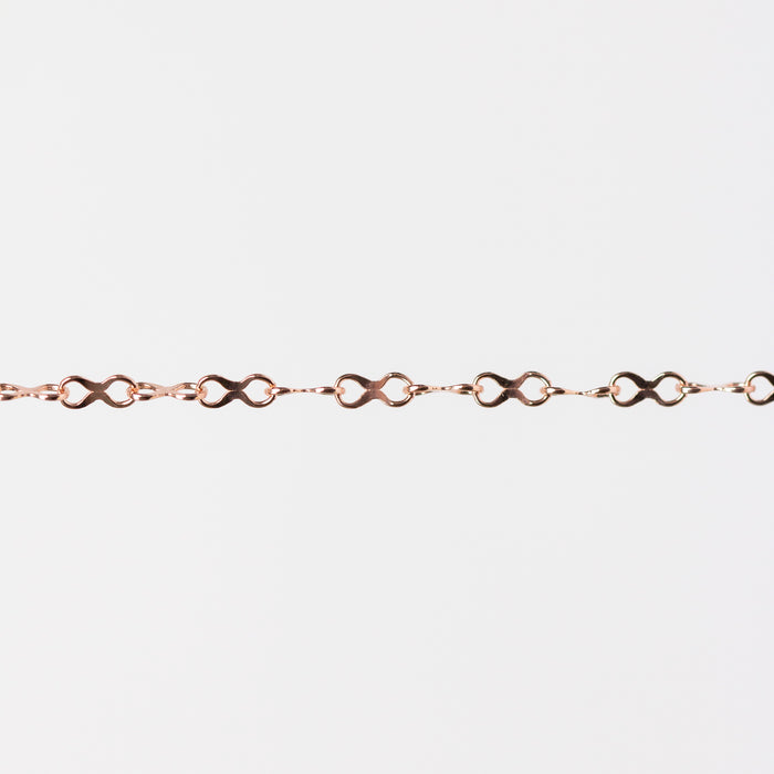 Rose gold infinity chain bracelet on a light gray background