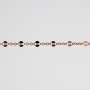 A close-up of a delicate rose gold chain bracelet featuring alternating hammered oval links in polished rose gold, set against a solid light gray background.