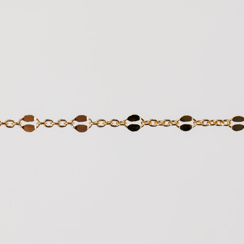 Gold bracelet with hammered links on a light gray background