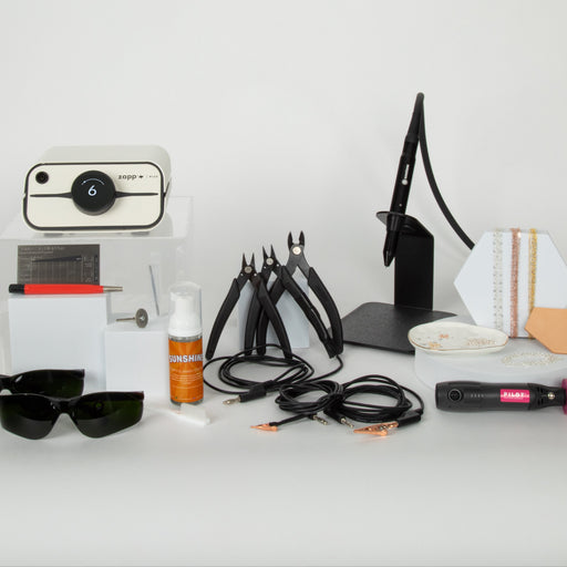 Collection of permanent jewelry tools and a white zapp plus 2 permanent jewelry welder on a white surface with a white background