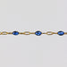 Gold permanent jewelry chain bracelet with sparkly blue enamel on a light gray background